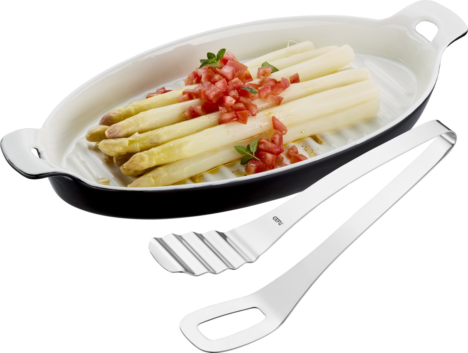 GEFU Servierplatte 40cm mit Zange PRESENTO Edelstahl-Spargelzange mit gewellter Greiffläche, schräg von oben in 3/4-Ansicht neben einer ovalen Auflaufform mit weißem Spargel und Tomatenwürfeln auf weißem Hintergrund.
