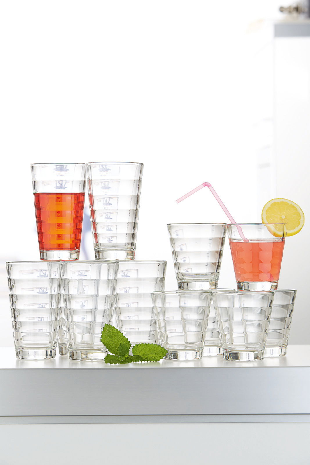 Becherset Wave 12-tlg. aus Glas, frontal fotografiert, mit Getränken und Zitronenscheibe dekoriert.