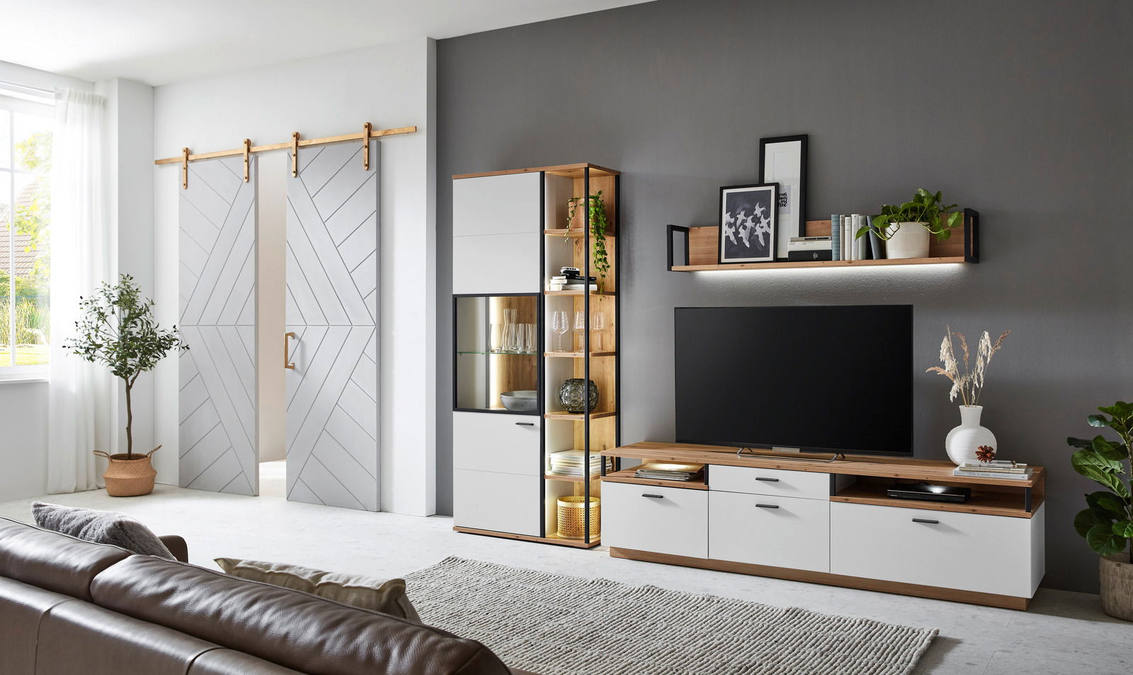 Moderne Wohnzimmer-Wandkombination mit TV-Schrank, Vitrine und Regal in Holz- und Weißtönen, seitliche Perspektive