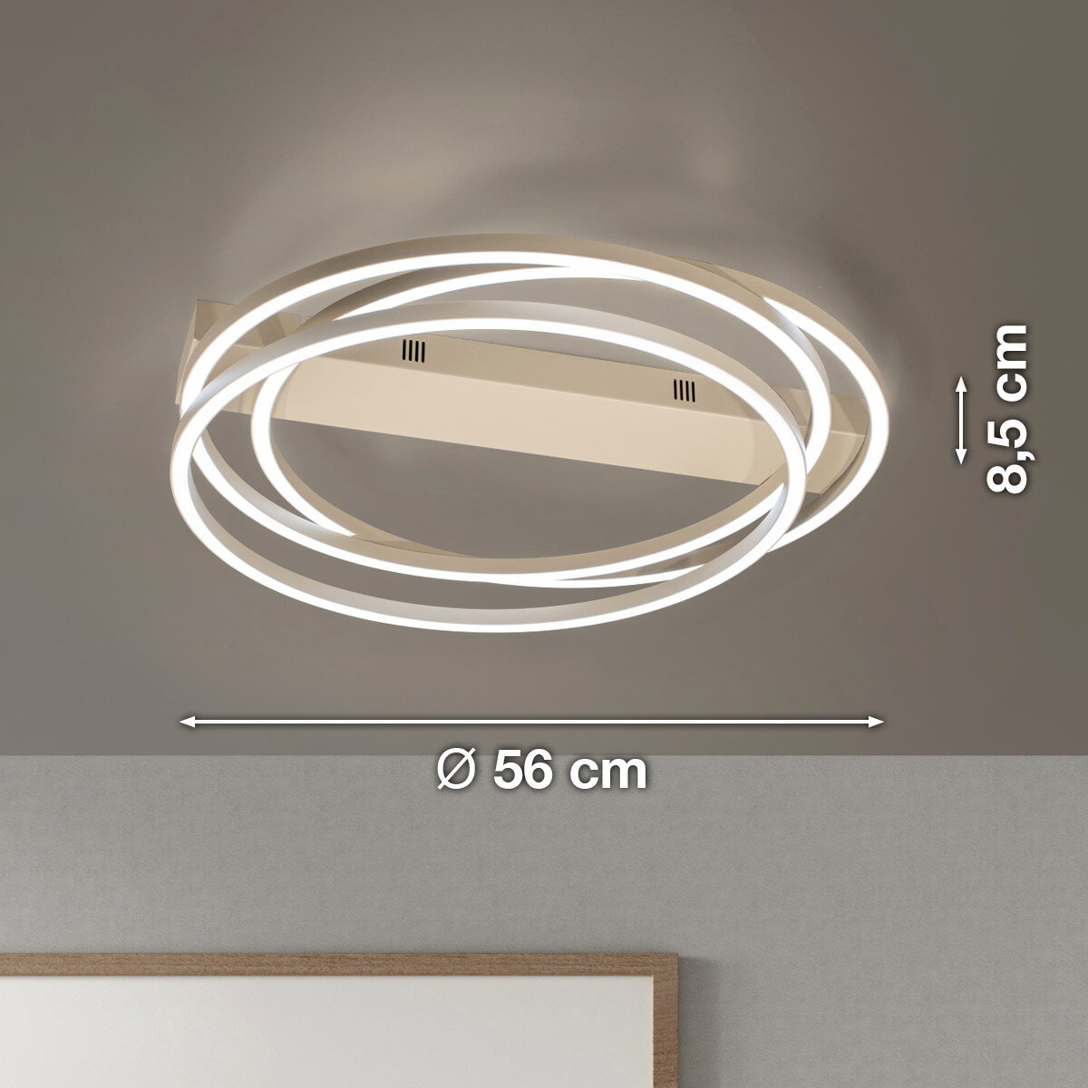 Moderne LED-Deckenleuchte in Weiß mit drei leuchtenden, ineinander verschlungenen Ringen, Ø 56 cm und Höhe 8,5 cm, Ansicht schräg von unten an der Decke montiert