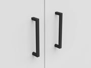 Nahaufnahme von zwei schwarzen Griffen an einer weißen Schranktür, frontal betrachtet.