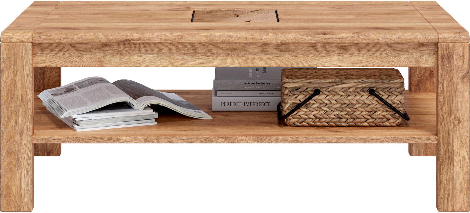 Massiver Couchtisch aus hellem Holz mit Ablagefach, frontal in Augenhöhe fotografiert; auf der unteren Ablage liegen Zeitschriften, Bücher und ein geflochtener Korb.