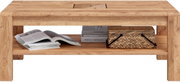 Massiver Couchtisch aus hellem Holz mit Ablagefach, frontal in Augenhöhe fotografiert; auf der unteren Ablage liegen Zeitschriften, Bücher und ein geflochtener Korb.