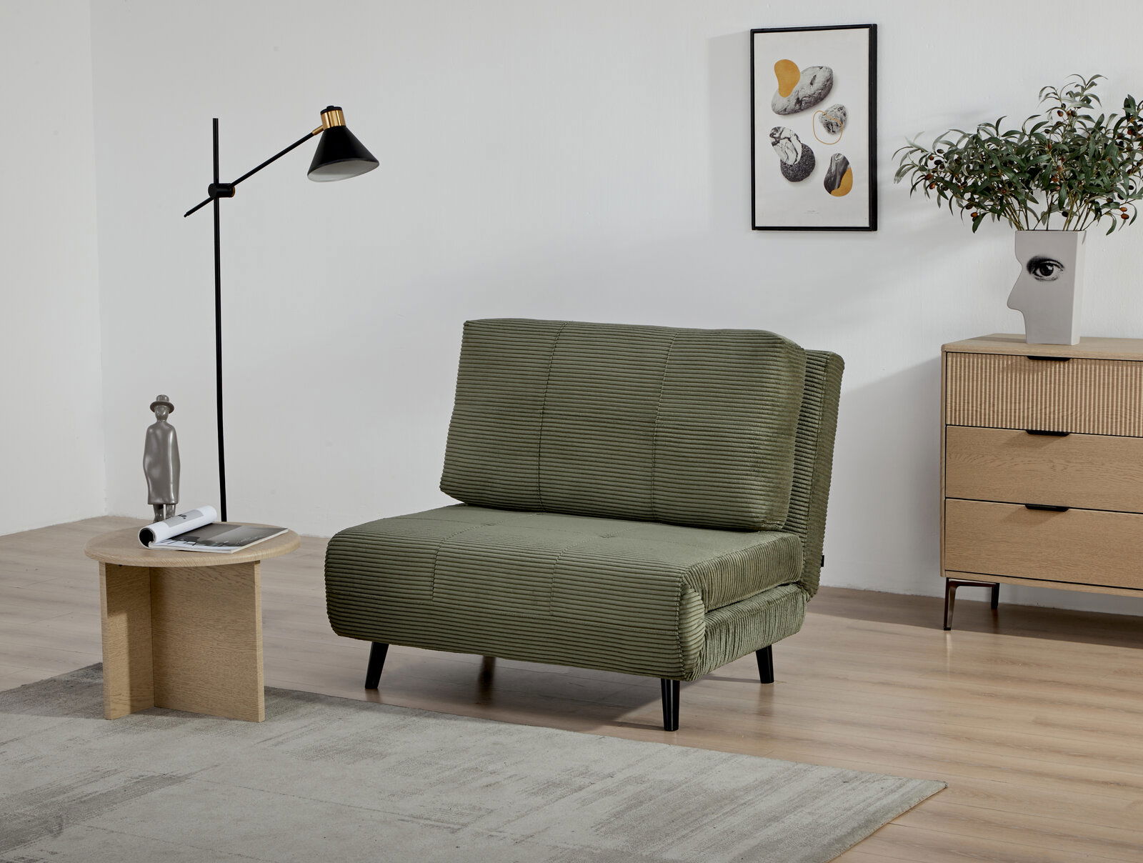 Grüner Funktionssessel in einem modernen Wohnzimmer, seitliche Perspektive, mit Stehlampe, Beistelltisch und Kommode im Hintergrund.