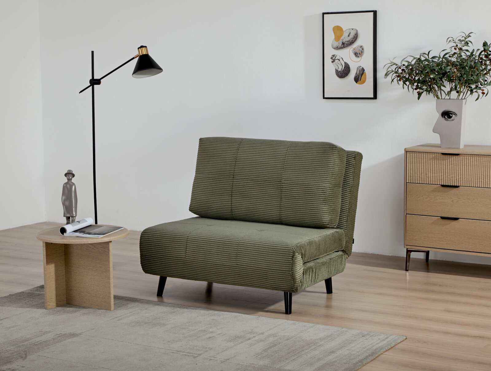 Groene fauteuil in een moderne woonkamer, zijaanzicht, met staande lamp, bijzettafeltje en dressoir op de achtergrond.