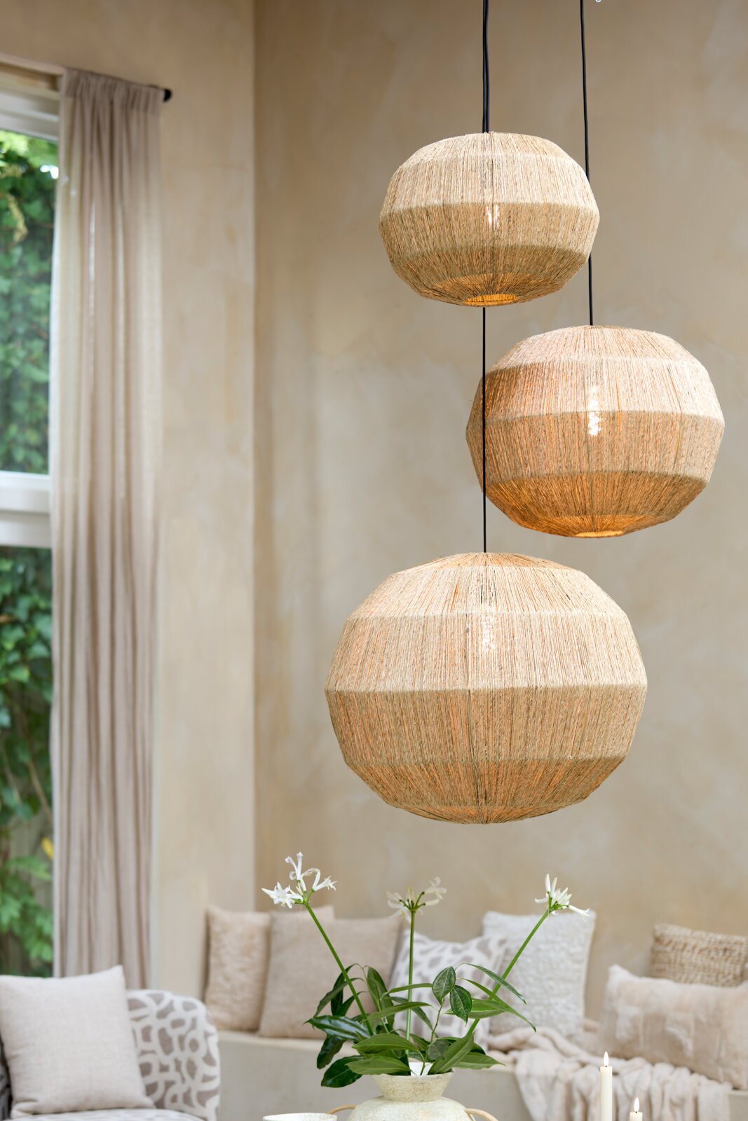 Drie hanglampen van natuurlijk materiaal in een gezellige woonkamer, zijaanzicht