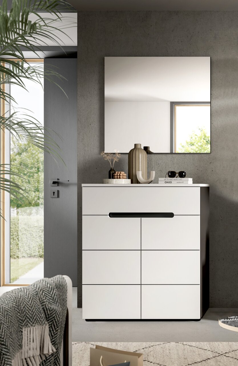 MID.YOU Garderobenkombination CANU Modernes weißes Sideboard/Kommode mit schwarzer Griffleiste vor Betonwand, darüber rechteckiger Wandspiegel; dekoriert mit Vasen und Büchern, Perspektive: frontale Ansicht auf Augenhöhe.