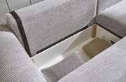Nahaufnahme einer grauen Eckcouch mit Stauraum, geöffnet, mit Kissen und Decke. Perspektive von oben.
