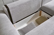 Nahaufnahme einer grauen Eckcouch mit Stauraum, geöffnet, mit Kissen und Decke. Perspektive von oben.