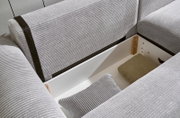 Nahaufnahme einer grauen Eckcouch mit Stauraum, geöffnet, mit Kissen und Decke. Perspektive von oben.