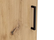 Nahaufnahme einer Holztür mit natürlicher Maserung und einem modernen schwarzen Griff, seitliche Perspektive.