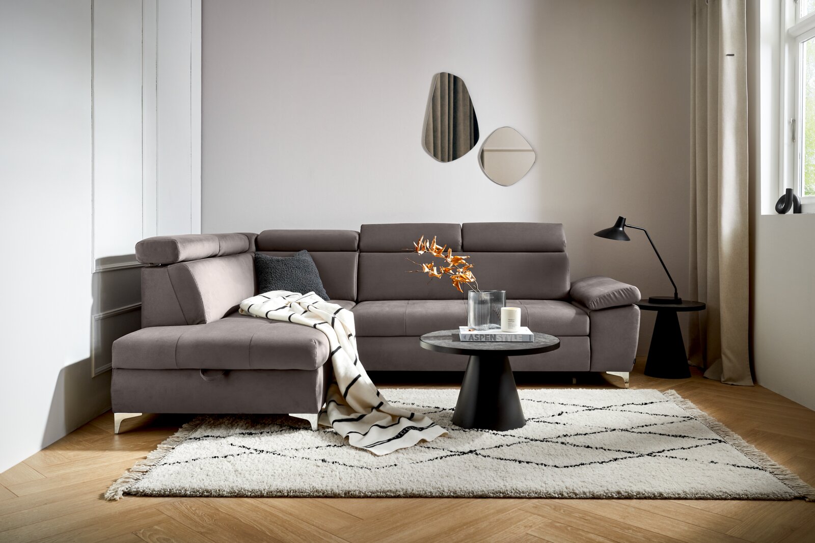 Osca Ecksofa RAUL Graue Rundecke (L) in einem modernen Wohnzimmer, mit einem Beistelltisch und Dekorationen, aus der Perspektive von vorne links.