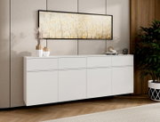 Modernes, weißes Sideboard mit grifflosen Fronten und klaren Linien, frontale Perspektive, dekoriert mit Vasen und Büchern in einem stilvollen Wohnzimmer unter einem großen Wandbild.