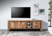 Frontale Ansicht eines Lowboards aus Holz mit zwei Türen, zwei Schubladen und einem offenen Fach mit Beleuchtung, dekoriert mit Korallen und Muscheln, vor einer weißen Wand mit einem großen Fernseher und gerahmten Bildern.