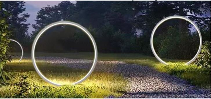 Erdspießleuchte ZIRKULU in einem Garten bei Nacht, leuchtende Ringe entlang eines Kieswegs, seitliche Perspektive