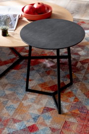 Moderne bijzettafel met een zwart, rond tafelblad en slanke metalen poten, gezien vanaf de zijkant.