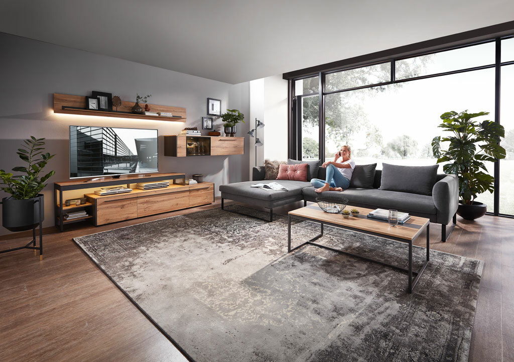 Moderne Wohnzimmereinrichtung mit Sideboard, TV-Aufsatz, Couchtisch und Wohnwand in Holzoptik, seitliche Perspektive.