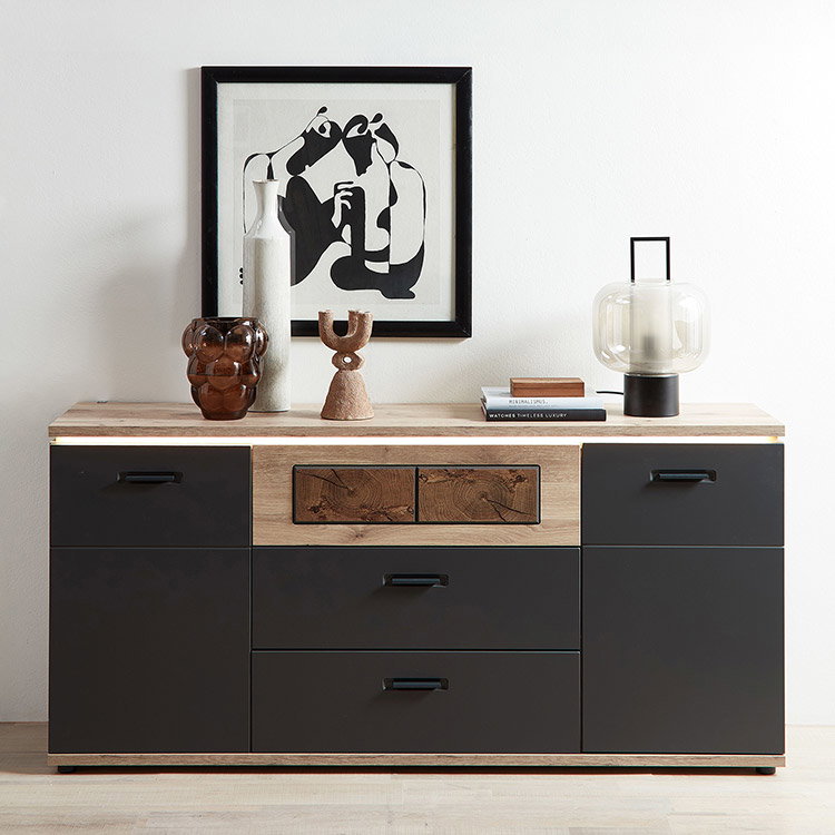 Sideboard in Holz-Schwarz mit Deko, Vase und Bild an weißer Wand.