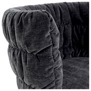 Nahaufnahme eines grauen, gepolsterten Armlehnstuhls mit weichem Stoffbezug, seitliche Perspektive.