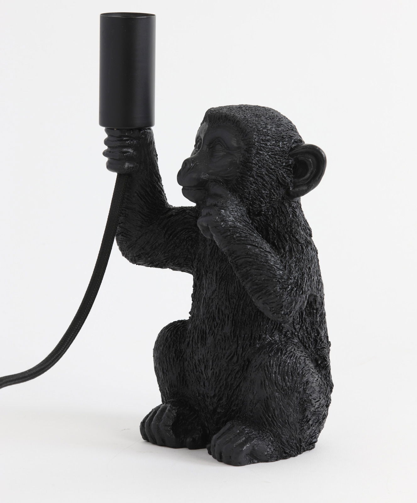 Schwarze Tischleuchte in Form eines Affen, der eine Lampenfassung in der Hand hält. Seitliche Perspektive.