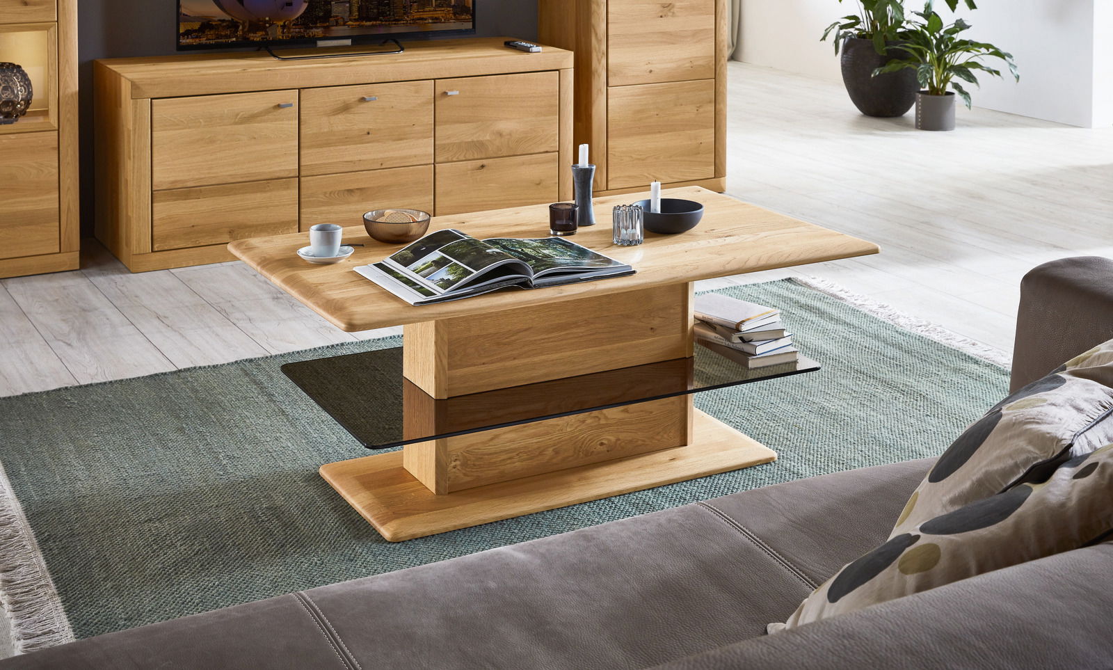 Wöstmann Markenmöbel Couchtisch AURUM Moderner Couchtisch aus Holz mit rechteckiger Tischplatte und stabiler Mittelsäule, umgeben von gemütlichem Wohnzimmerambiente. Perspektive von schräg oben.