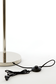 Nahaufnahme der Basis einer Stehleuchte mit glänzendem Metallfuß und schwarzem Kabel mit Fußschalter.