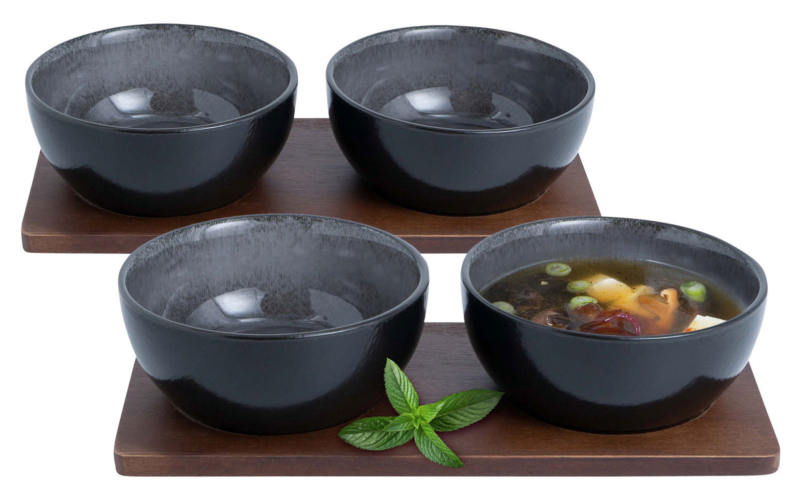Vier anthrazitfarbene Miso-Schalen auf Holzuntersetzern, eine Schale mit Suppe gefüllt, aus leicht erhöhter Perspektive.