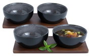 Vier anthrazitfarbene Miso-Schalen auf Holzuntersetzern, eine Schale mit Suppe gefüllt, aus leicht erhöhter Perspektive.