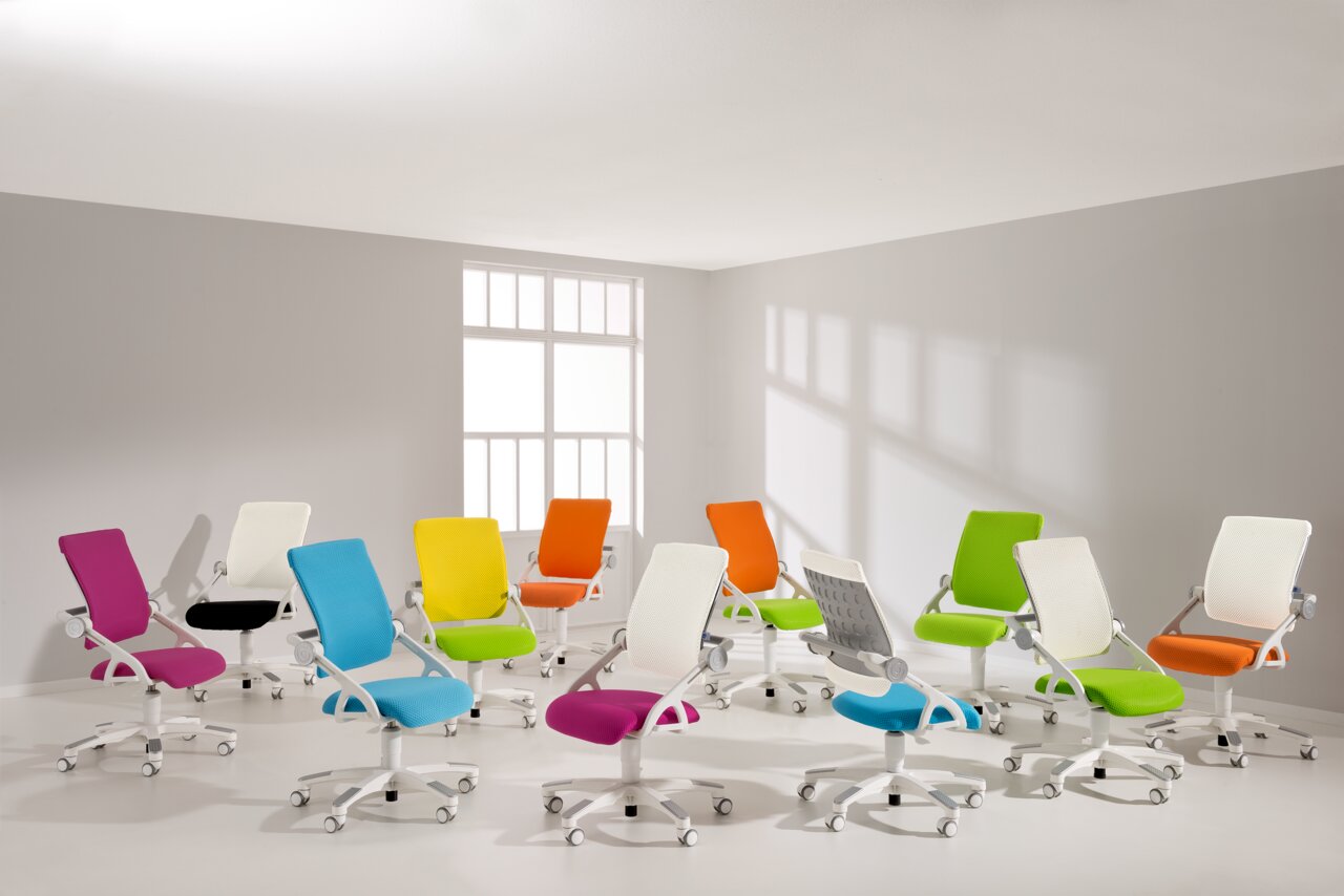 Mehrere bunte Drehstühle in einem hellen Raum, von der Seite betrachtet.