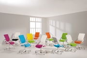 Mehrere bunte Drehstühle in einem hellen Raum, von der Seite betrachtet.