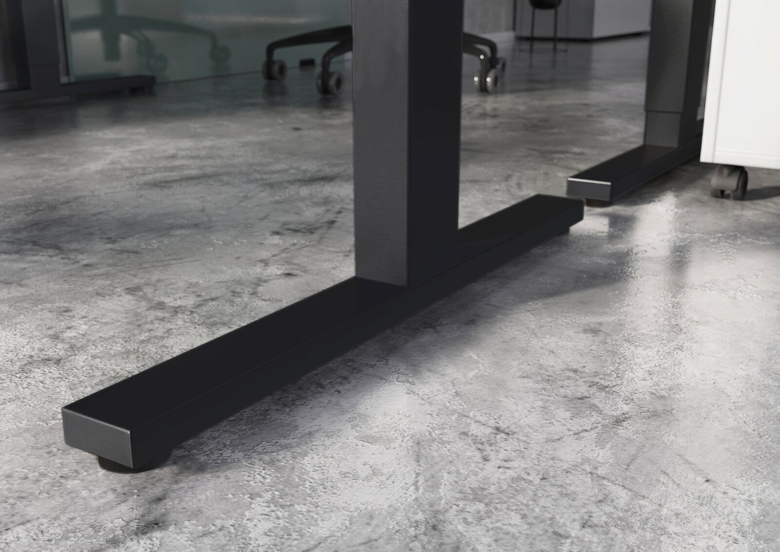 Nahaufnahme der stabilen, schwarzen Metallbeine eines höhenverstellbaren E-Schreibtisches auf einem modernen Betonboden.