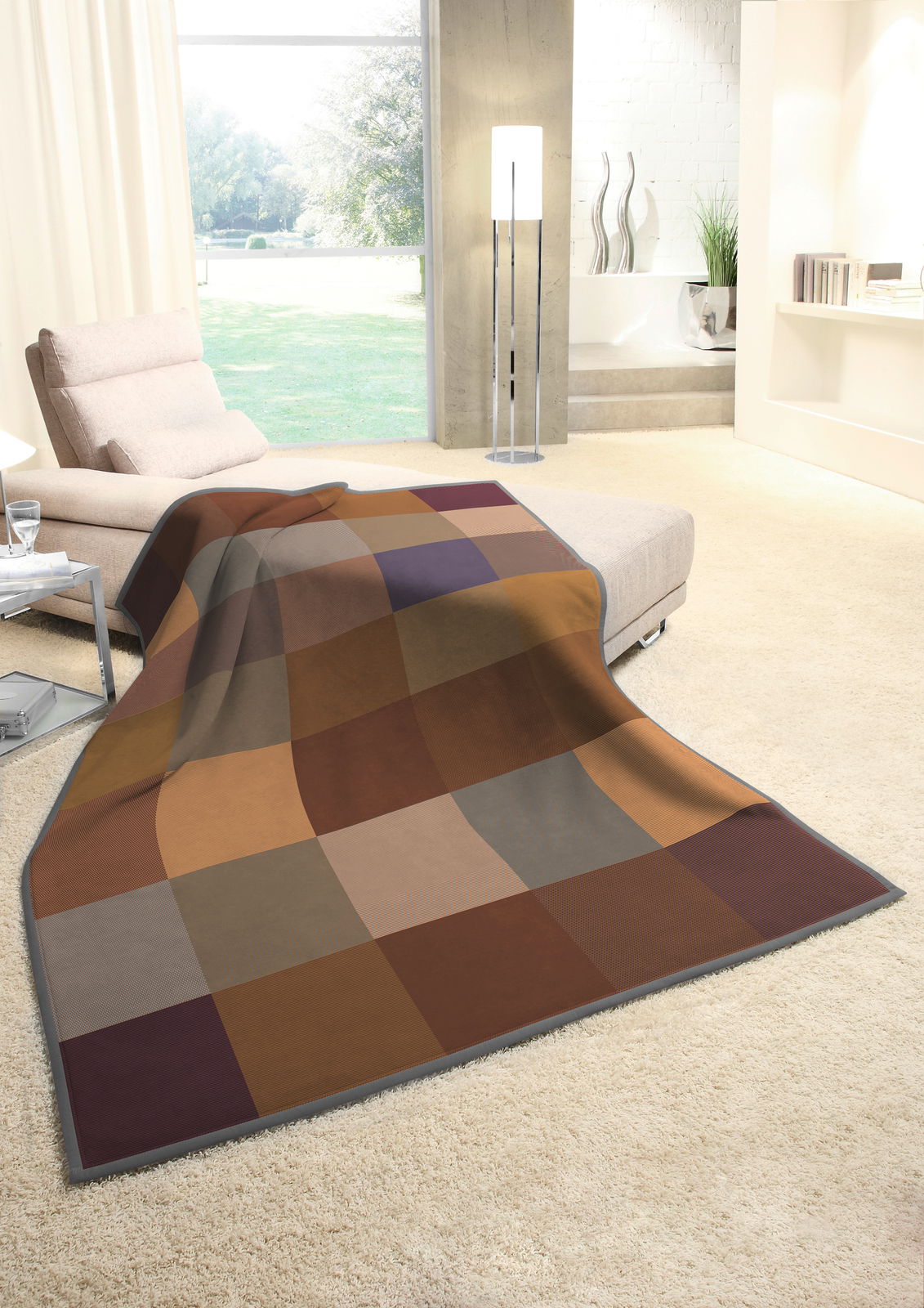 Gemütliche Wohndecke in warmen Erdtönen mit Karomuster, drapiert über einem Sofa in einem modernen Wohnzimmer mit Blick auf den Garten.