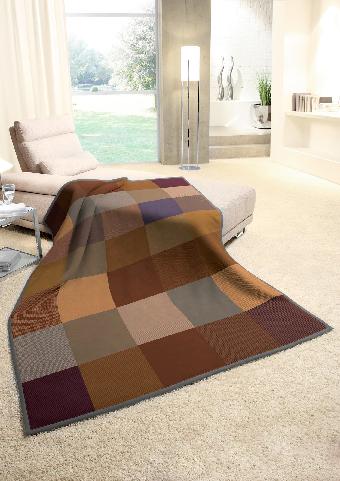 Gemütliche Wohndecke in warmen Erdtönen mit Karomuster, drapiert über einem Sofa in einem modernen Wohnzimmer mit Blick auf den Garten.