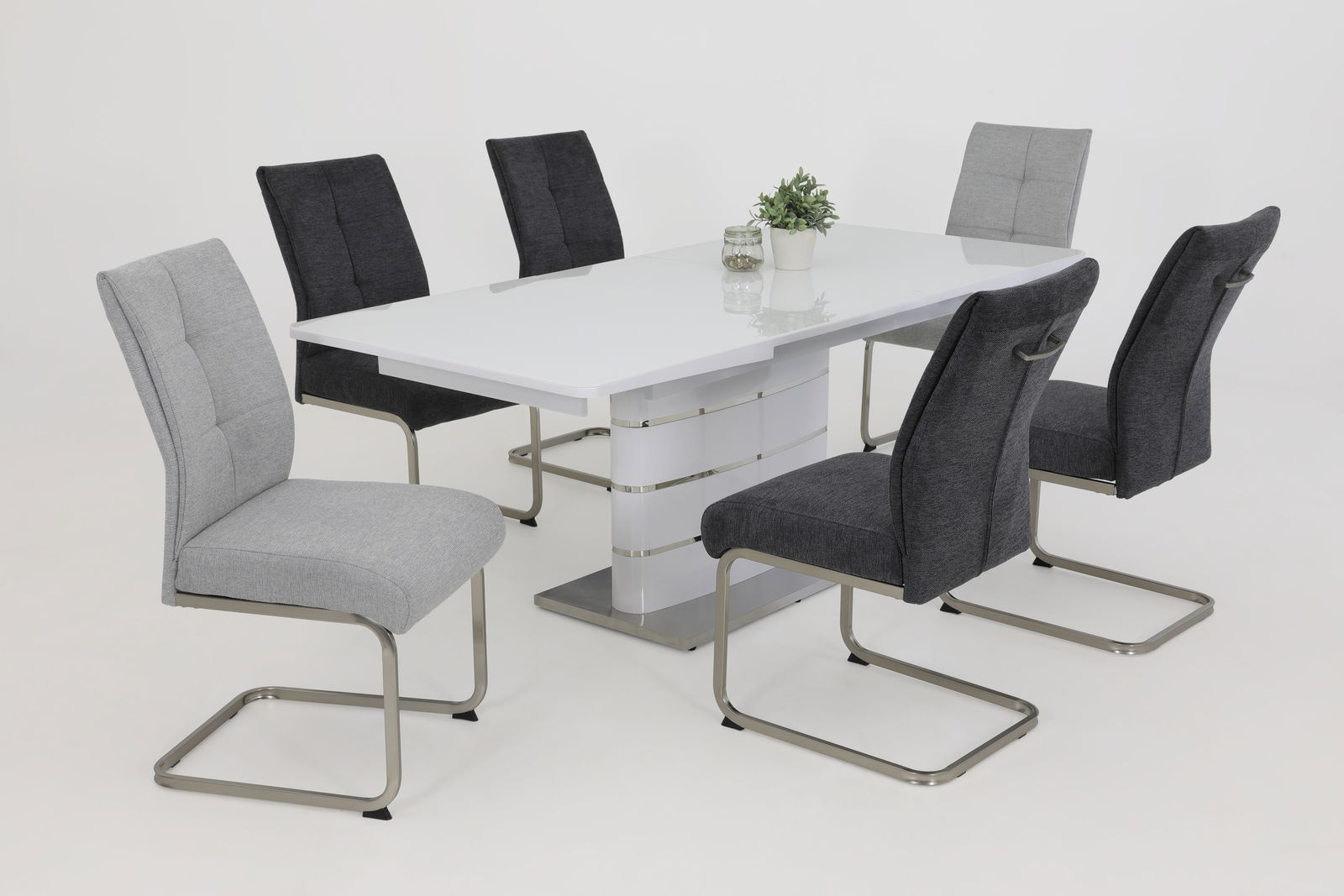 Esszimmer mit modernem weißen Tisch und sechs Schwingstühlen in Grau- und Schwarztönen, seitliche Perspektive