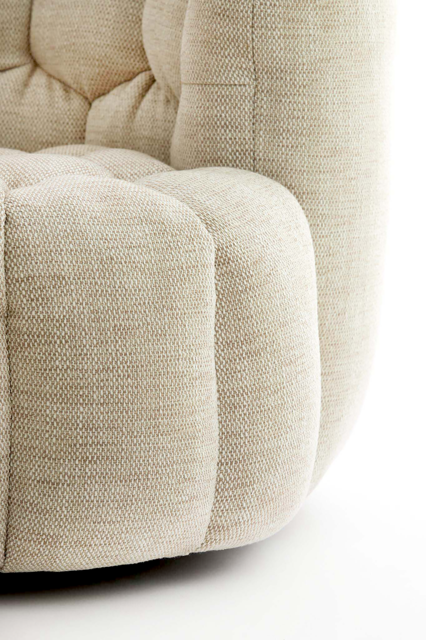 Nahaufnahme eines beigen Sessels mit strukturierter Polsterung, seitliche Perspektive