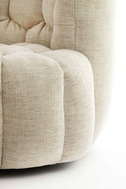 Nahaufnahme eines beigen Sessels mit strukturierter Polsterung, seitliche Perspektive