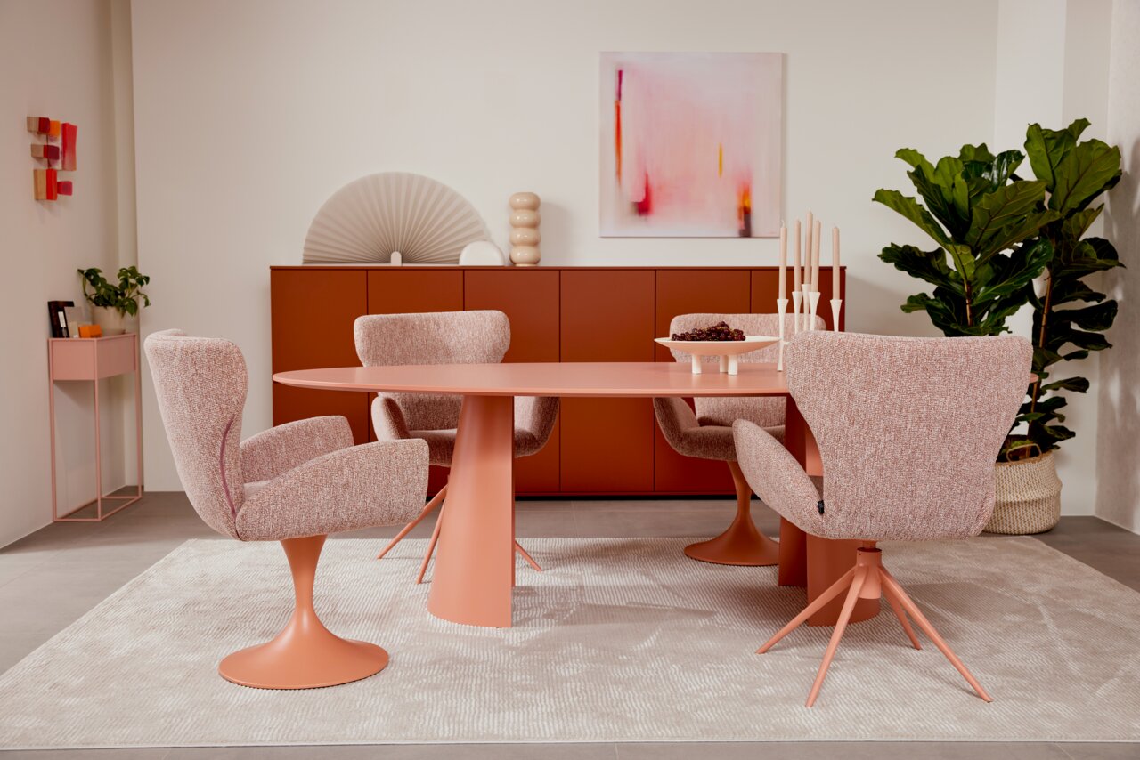 Musterring Esstisch MR JUSTB! Moderner Esstisch in Rosa mit passenden Stühlen, umgeben von stilvoller Dekoration und Pflanzen, aus der Frontalperspektive fotografiert.