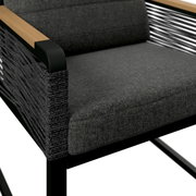 Close-up van een moderne tuinstoel met een grijze stoffen bekleding, een zwart metalen frame en houten armleuningen.