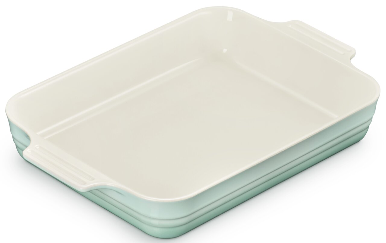 Rechthoekige keramische ovenschaal in mintgroen met crèmekleurige binnenkant en handvatten aan de zijkanten, schuin van bovenaf in driekwartperspectief afgebeeld op een witte achtergrond