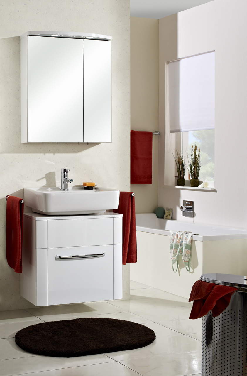 Moderner Spiegelschrank im Badezimmer, frontal betrachtet, über einem Waschbecken mit roten Handtüchern.