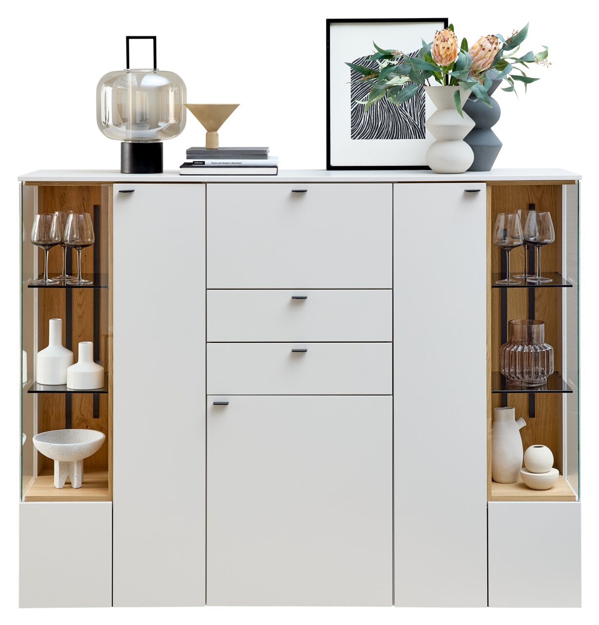 Frontale Ansicht eines modernen Highboards mit weißen Türen und Schubladen, flankiert von Glasvitrinen mit dekorativen Objekten.