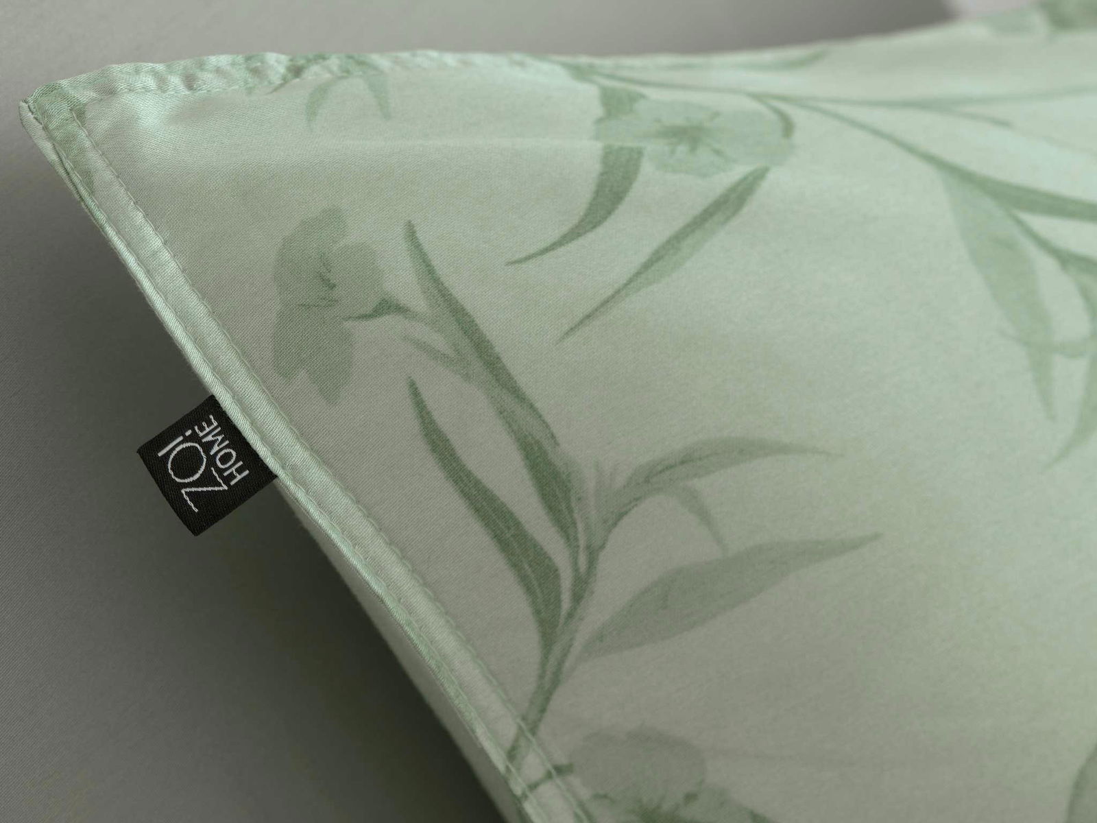 Nahaufnahme einer Bettwäsche mit floralem Muster in Grün, perspektivisch von der Ecke aufgenommen.