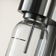 Nahaufnahme einer Wasserflasche in einem modernen Wassersprudler aus Edelstahl, seitliche Perspektive.