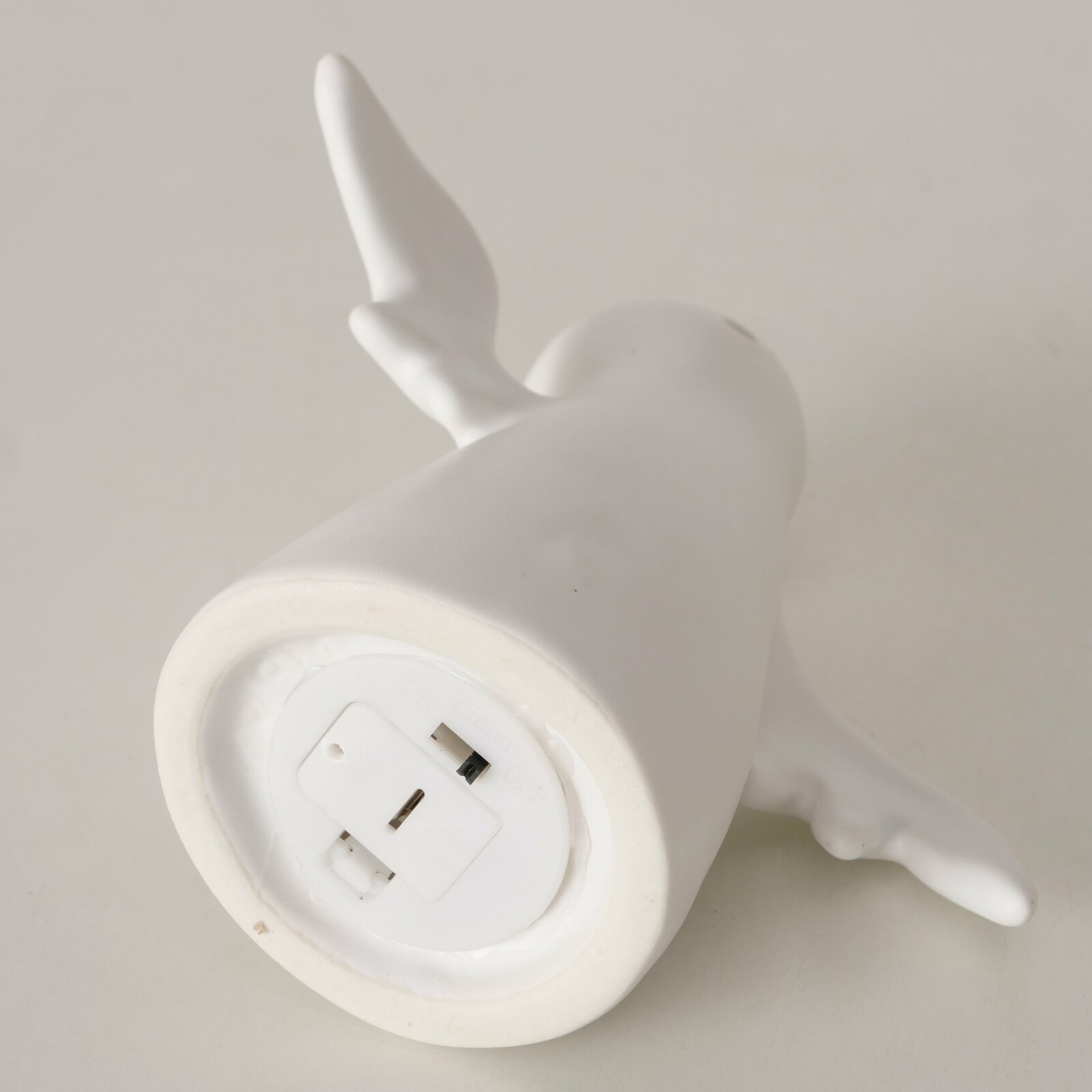 Unteransicht einer weißen Geisterfigur mit Flügeln, zeigt die Unterseite mit Batteriefach.