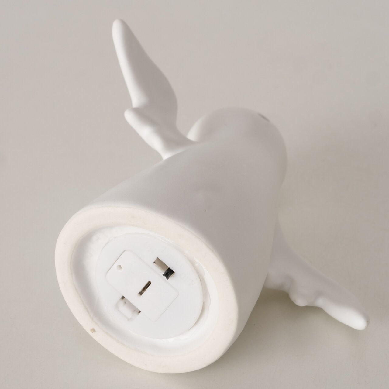 Unteransicht einer weißen Geisterfigur mit Flügeln, zeigt die Unterseite mit Batteriefach.