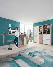 Moderner Schreibtisch mit höhenverstellbarer Funktion und Schwinghocker in einem hellen Büro, seitliche Perspektive.