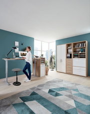 Moderner Schreibtisch mit höhenverstellbarer Funktion und Schwinghocker in einem hellen Büro, seitliche Perspektive.