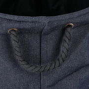 Nahaufnahme eines Wäschesammlers aus Denim-Stoff mit einem robusten Seilgriff, von oben betrachtet.