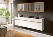 Modernes, wandhängendes Sideboard in Weiß mit Holz-Akzentfuge unter einem breiten Spiegel mit Holzrahmen in einem hellen Wohnraum; Perspektive: leicht schräg von vorne rechts.