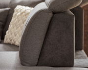 Seitenansicht einer modernen, grauen Rundecke mit verstellbarer Kopfstütze und dekorativem Kissen.